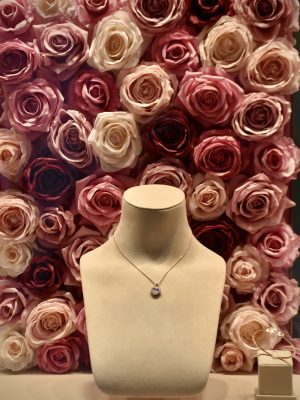 broderie diamant Un mannequin avec un collier devant un mur de roses