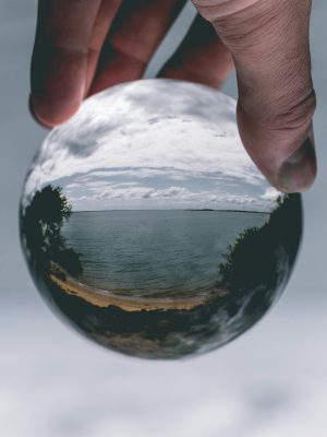 broderie diamant Une main tenant une boule de cristal avec une plage et une étendue d'eau