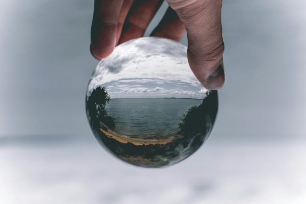 broderie diamant Une main tenant une boule de cristal avec une plage et une étendue d'eau
